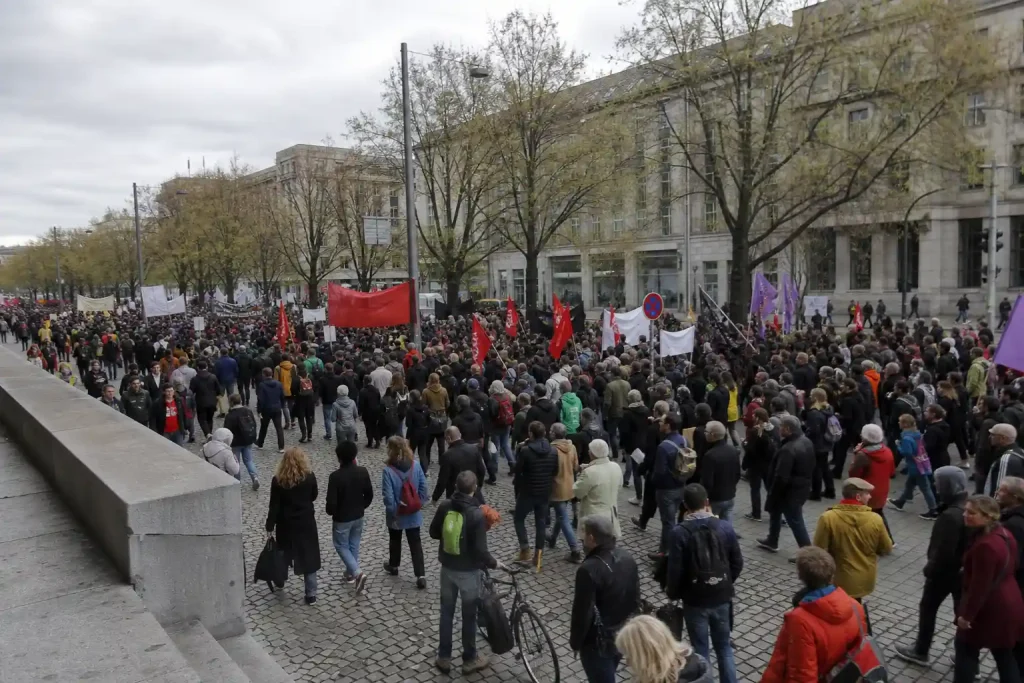 Folkmassan på Vänsterns första maj-demonstration fyller en stadsgata under en mulen vårdag.