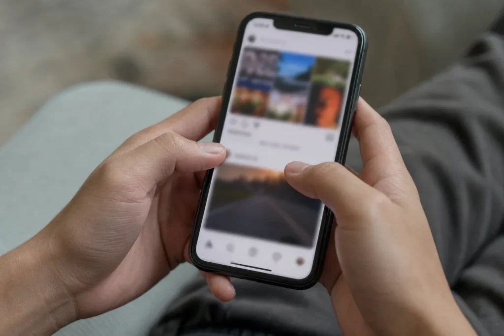 Händer som håller en smartphone med ett suddigt socialt medieflöde på skärmen, ett ögonblick innan nästa svep i Sandra Sti...