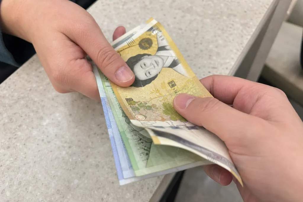 Två händer som överlämnar sydkoreanska wonssedlar i ett avslappnat handslag.