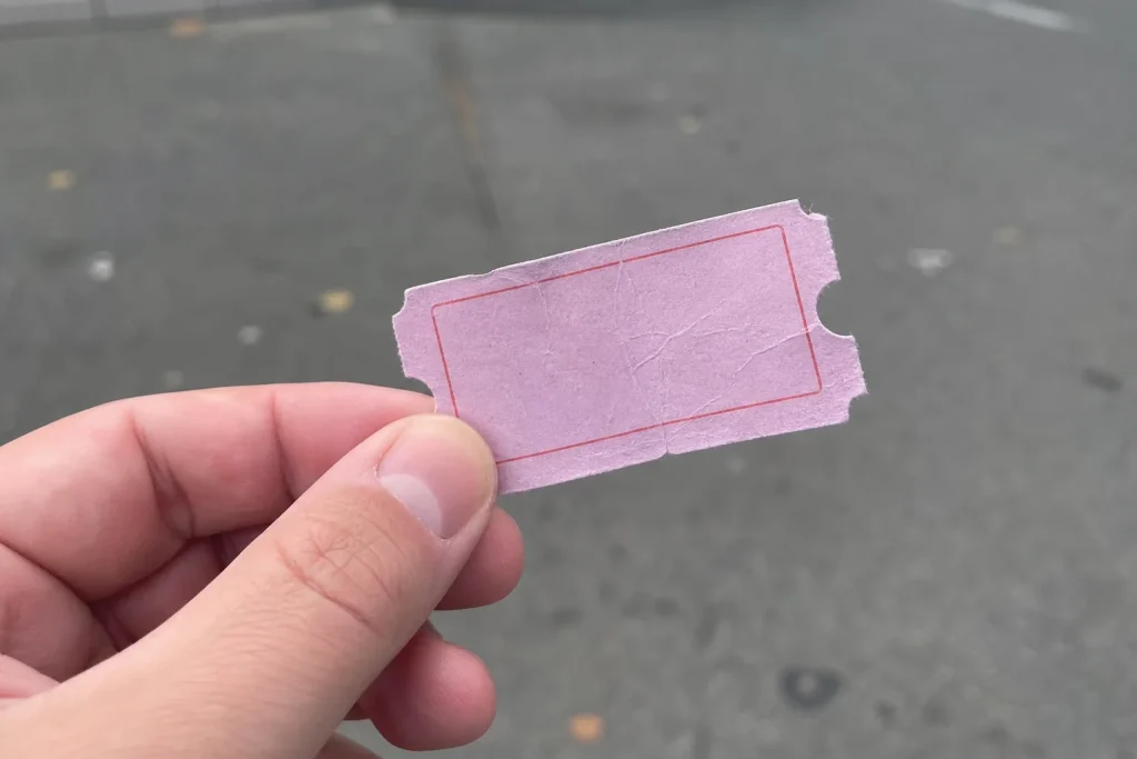 En hand håller löst i en skrynklig biljett från ett nöjesfält medan Apple är återigen världens högst värderade företag.