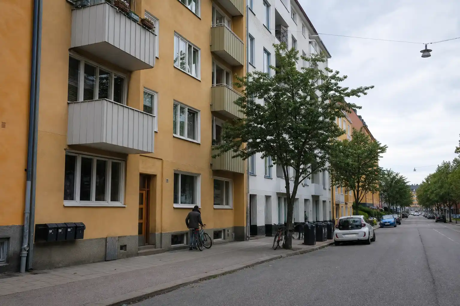 En svensk bostadsgata en overcast dag med lägenhetshus och cyklar, relevant för boendekostnader 2027.