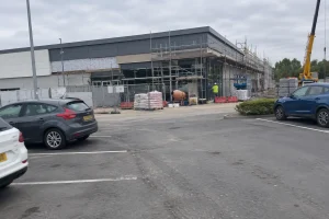 En Lidlbutik under byggnation med byggställningar och en arbetare på plats, del av pågående Lidl butiksexpansion.